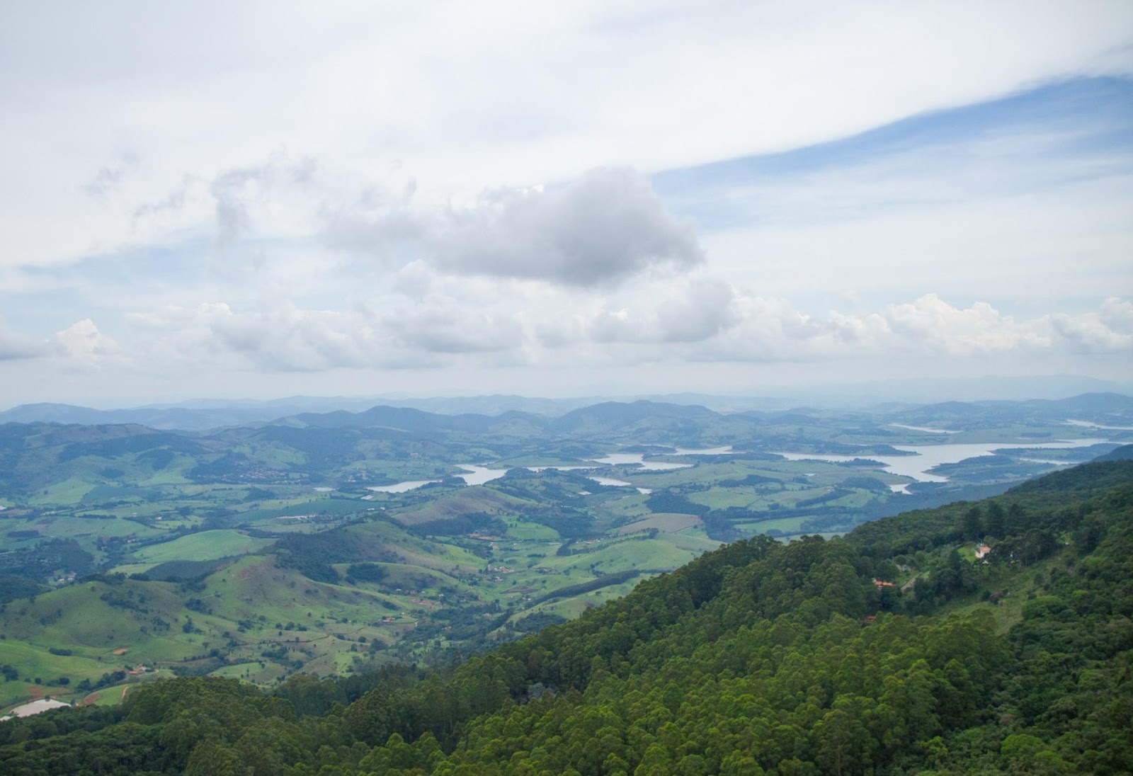 A view of a valley with trees and a lakeAI-generated content may be incorrect.